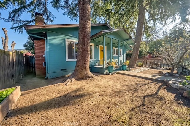 view of front of property with crawl space, a porch, a chimney, and fence