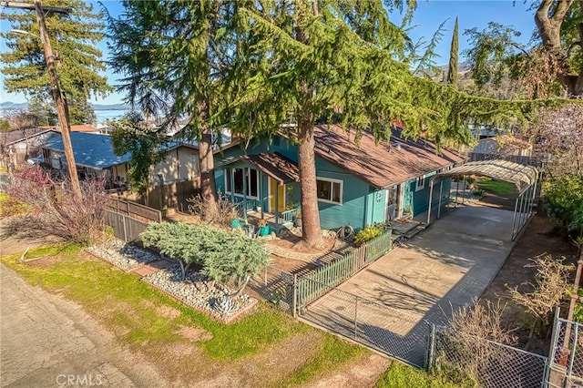 view of front facade featuring a detached carport, concrete driveway, and a fenced front yard