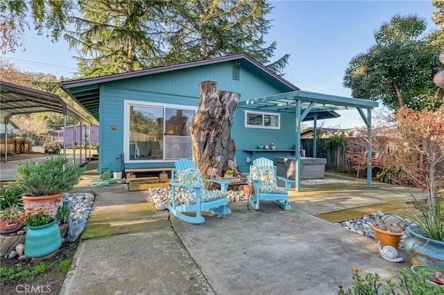 back of house with a detached carport, a patio area, fence, and a hot tub