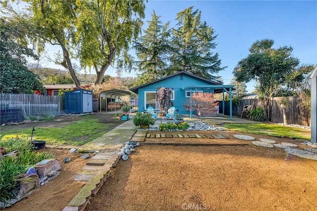 back of house featuring a fenced backyard, a carport, an outdoor structure, a storage unit, and a patio area