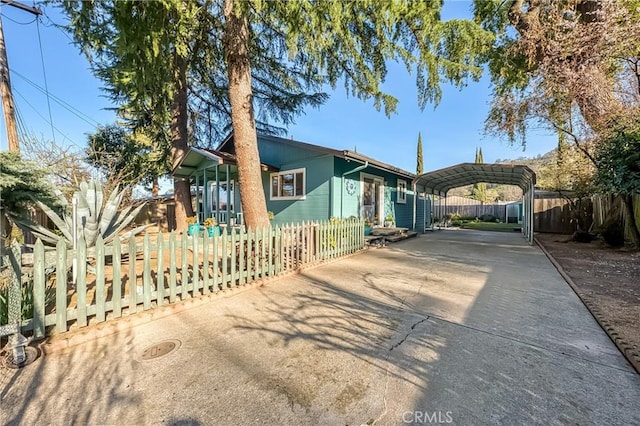 view of front of house featuring a fenced front yard, a detached carport, and concrete driveway