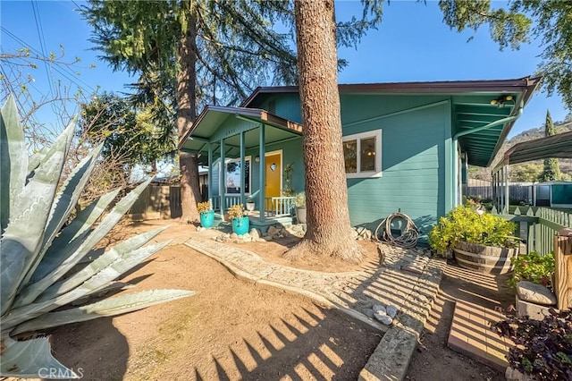 back of house with a carport, fence, and covered porch