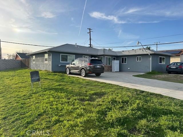 ranch-style house with a front lawn, fence, driveway, and stucco siding