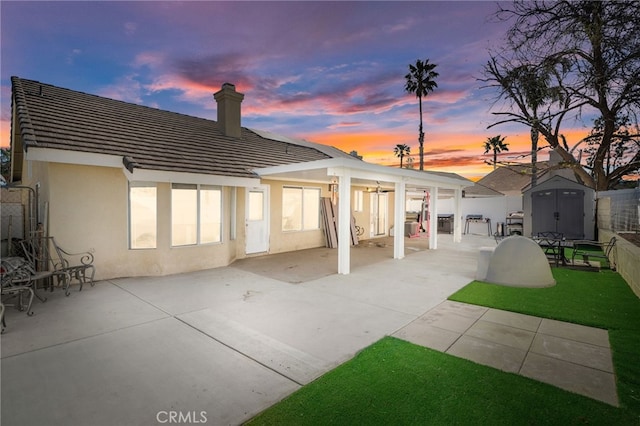 rear view of property with an outbuilding, a shed, stucco siding, and a patio