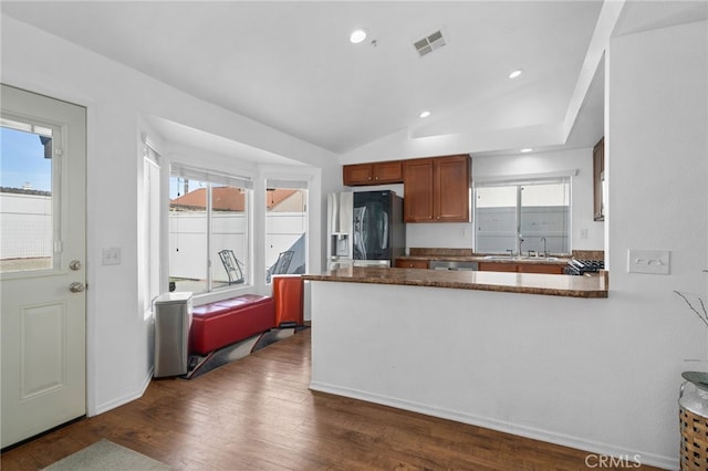 kitchen with visible vents, vaulted ceiling, a peninsula, stainless steel appliances, and dark wood-style flooring