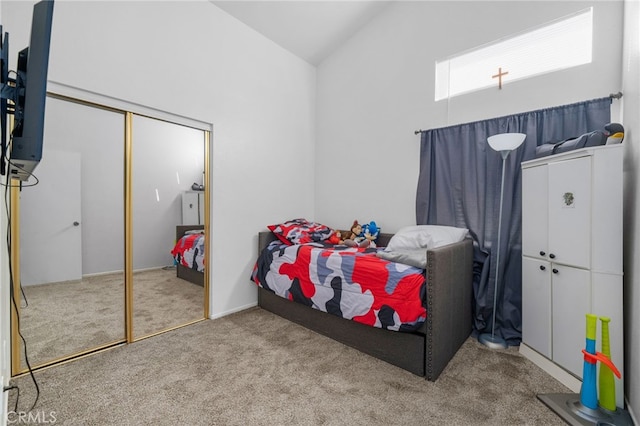 carpeted bedroom featuring a closet and high vaulted ceiling