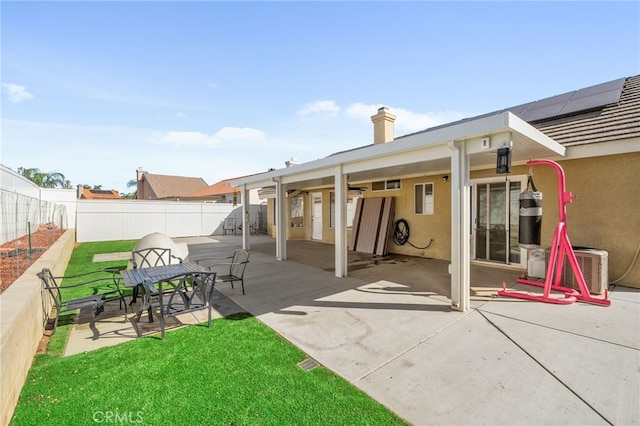 back of property with stucco siding, a chimney, a fenced backyard, a yard, and a patio