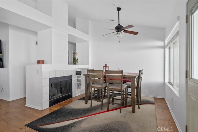 dining space with visible vents, a ceiling fan, wood finished floors, a fireplace, and baseboards