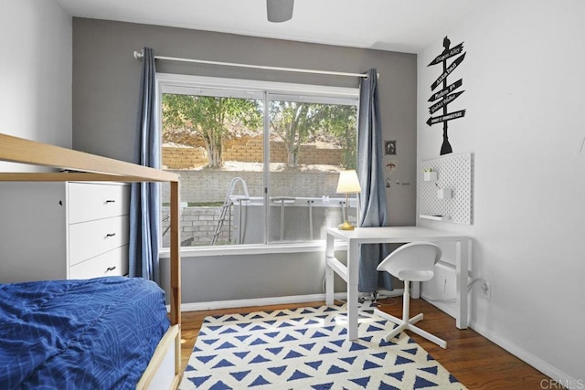 bedroom featuring multiple windows, baseboards, and wood finished floors