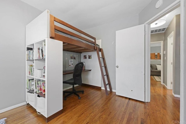 bedroom featuring visible vents, baseboards, and wood finished floors