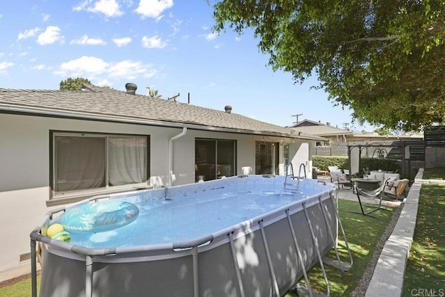 rear view of property with fence, roof with shingles, and stucco siding