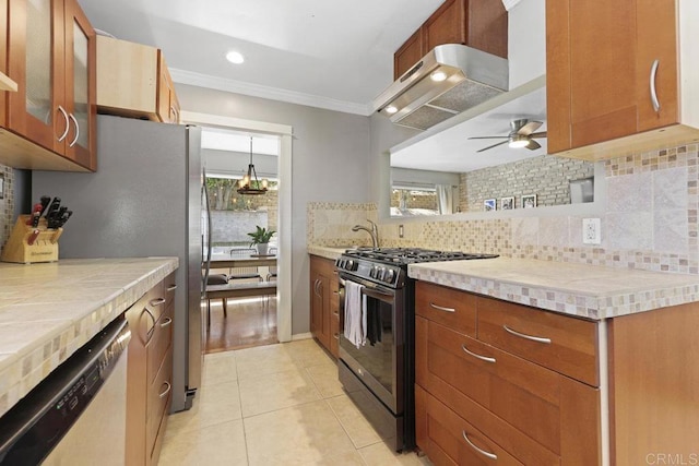 kitchen featuring light tile patterned floors, decorative backsplash, under cabinet range hood, appliances with stainless steel finishes, and crown molding