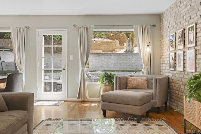 living area with wood finished floors and brick wall