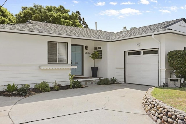 ranch-style house featuring concrete driveway, an attached garage, and roof with shingles