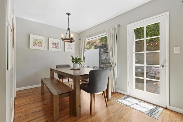 dining space with an inviting chandelier, baseboards, and light wood-style floors