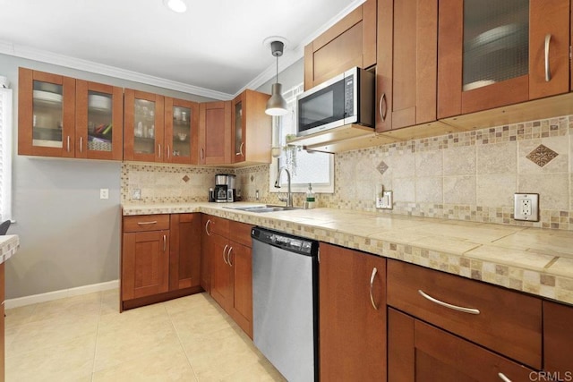 kitchen with ornamental molding, appliances with stainless steel finishes, brown cabinets, and a sink