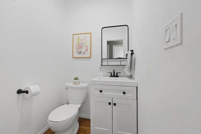 bathroom featuring baseboards, toilet, wood finished floors, and vanity