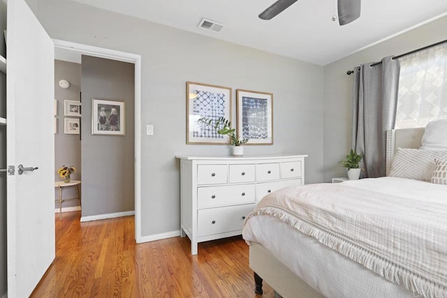 bedroom featuring visible vents, a ceiling fan, baseboards, and wood finished floors