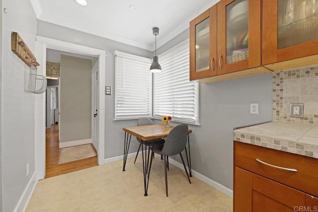 dining space with light tile patterned floors, baseboards, and crown molding