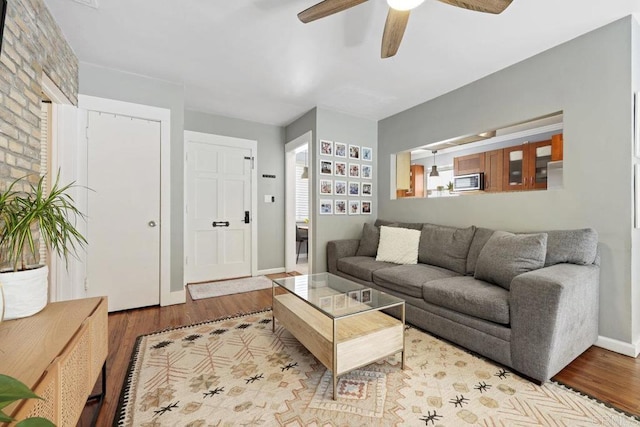 living room with a ceiling fan, wood finished floors, and baseboards