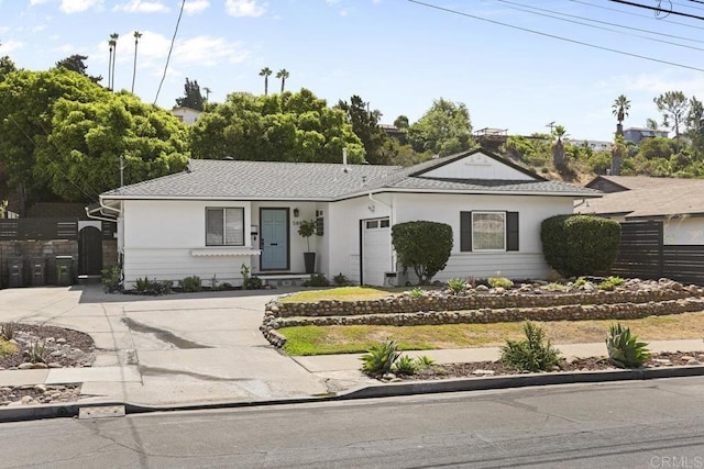 ranch-style house featuring a garage, driveway, and fence