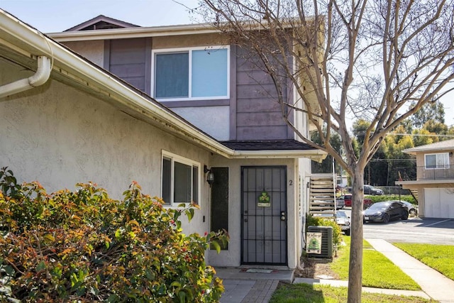 doorway to property with stucco siding and cooling unit