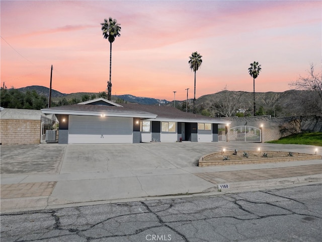 view of front of property featuring a mountain view, a garage, driveway, and a gate