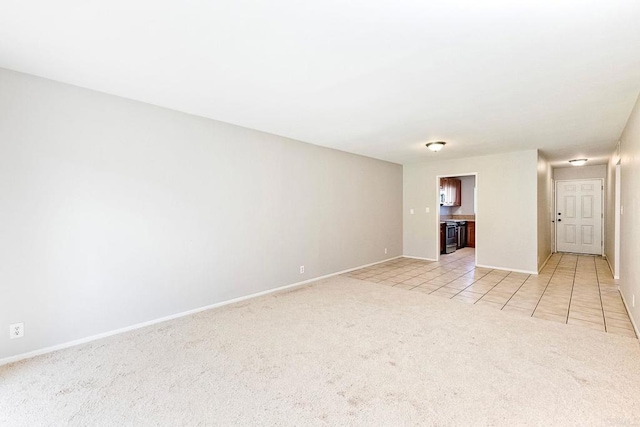 unfurnished room featuring baseboards, light colored carpet, and light tile patterned flooring