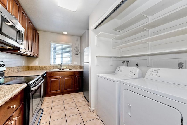 washroom featuring a sink, light tile patterned floors, laundry area, and washer and clothes dryer