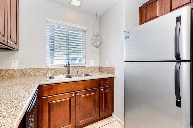 kitchen featuring light countertops, light tile patterned floors, freestanding refrigerator, and a sink