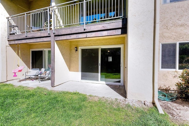 back of house with a patio area, stucco siding, and a balcony