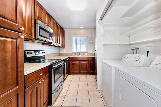 kitchen with washer and clothes dryer, light countertops, light tile patterned floors, stainless steel appliances, and a sink