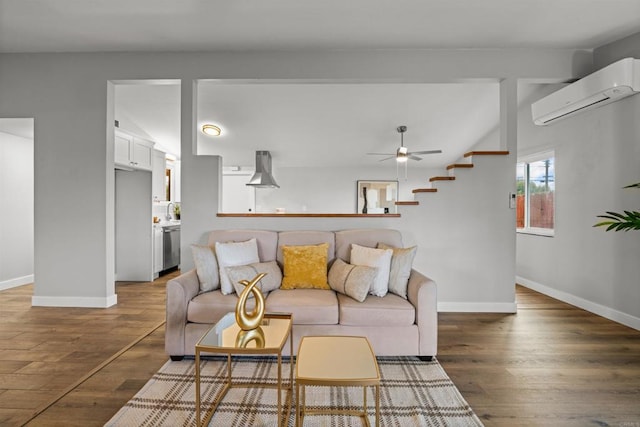 living room with baseboards, lofted ceiling, wood finished floors, and a wall mounted AC