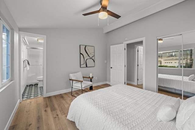 bedroom featuring a ceiling fan, wood finished floors, baseboards, lofted ceiling, and ensuite bathroom