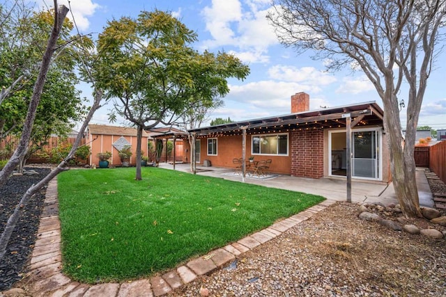 back of house with a lawn, a patio, a chimney, and a fenced backyard