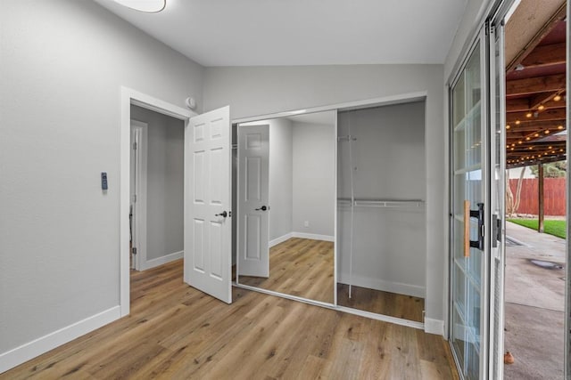 unfurnished bedroom featuring lofted ceiling, wood finished floors, baseboards, and a closet