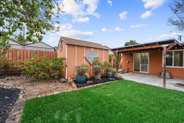 view of yard featuring a storage shed, an outdoor structure, fence, and a patio