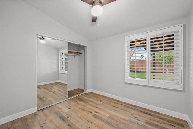 unfurnished bedroom featuring vaulted ceiling, wood finished floors, a closet, and baseboards