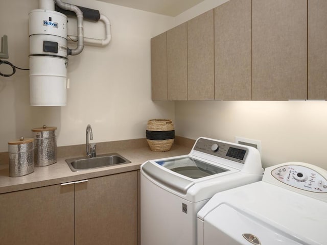 laundry area with washing machine and clothes dryer, cabinet space, and a sink