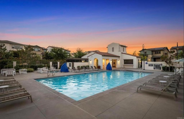 community pool with a patio area, area for grilling, and fence