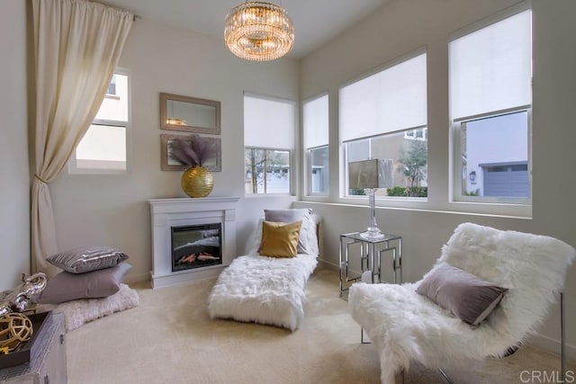 sitting room with a glass covered fireplace, a notable chandelier, and carpet floors