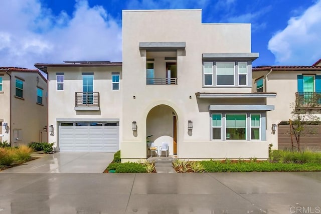 view of front facade featuring a balcony, an attached garage, driveway, and stucco siding