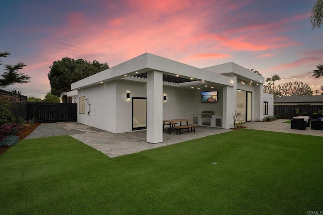 back of house with a patio, a yard, a fenced backyard, and stucco siding