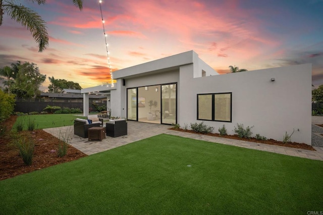 rear view of property with stucco siding, fence, a yard, outdoor lounge area, and a patio area