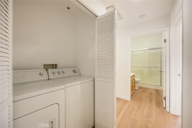 clothes washing area with light wood-style floors, independent washer and dryer, and laundry area