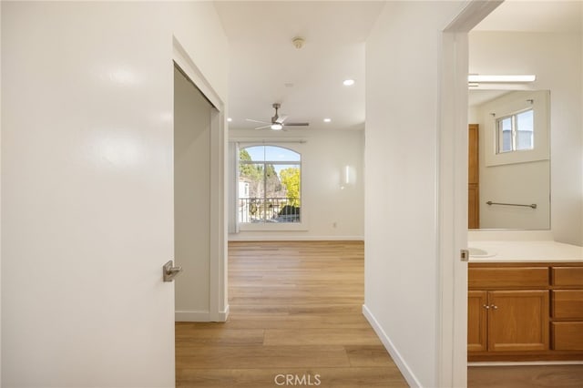 hallway featuring recessed lighting, baseboards, and light wood-style flooring