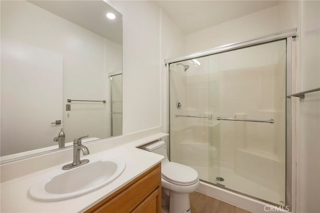 bathroom with toilet, recessed lighting, a stall shower, wood finished floors, and vanity