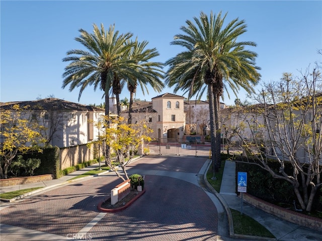 view of road featuring a gate, curbs, sidewalks, and a gated entry