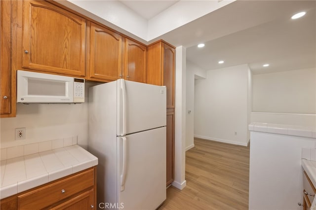 kitchen with recessed lighting, tile countertops, white appliances, and brown cabinets