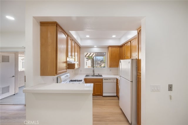 kitchen with white appliances, visible vents, light wood finished floors, a peninsula, and under cabinet range hood